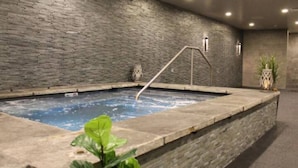 Ett spaområde med en stenmur, ett bubbelbad och en metallstege.