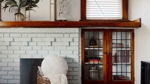 A room with a white brick fireplace, a wooden bookcase with books, and a wicker basket with a white towel. - Stunning 3BR - Near Cleveland Clinic Main Campus (Cleveland Heights)