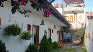 A white building with a balcony, a stone pathway, and potted plants. - Casa Refúgio das Águias na Praia do Preá (Cruz)