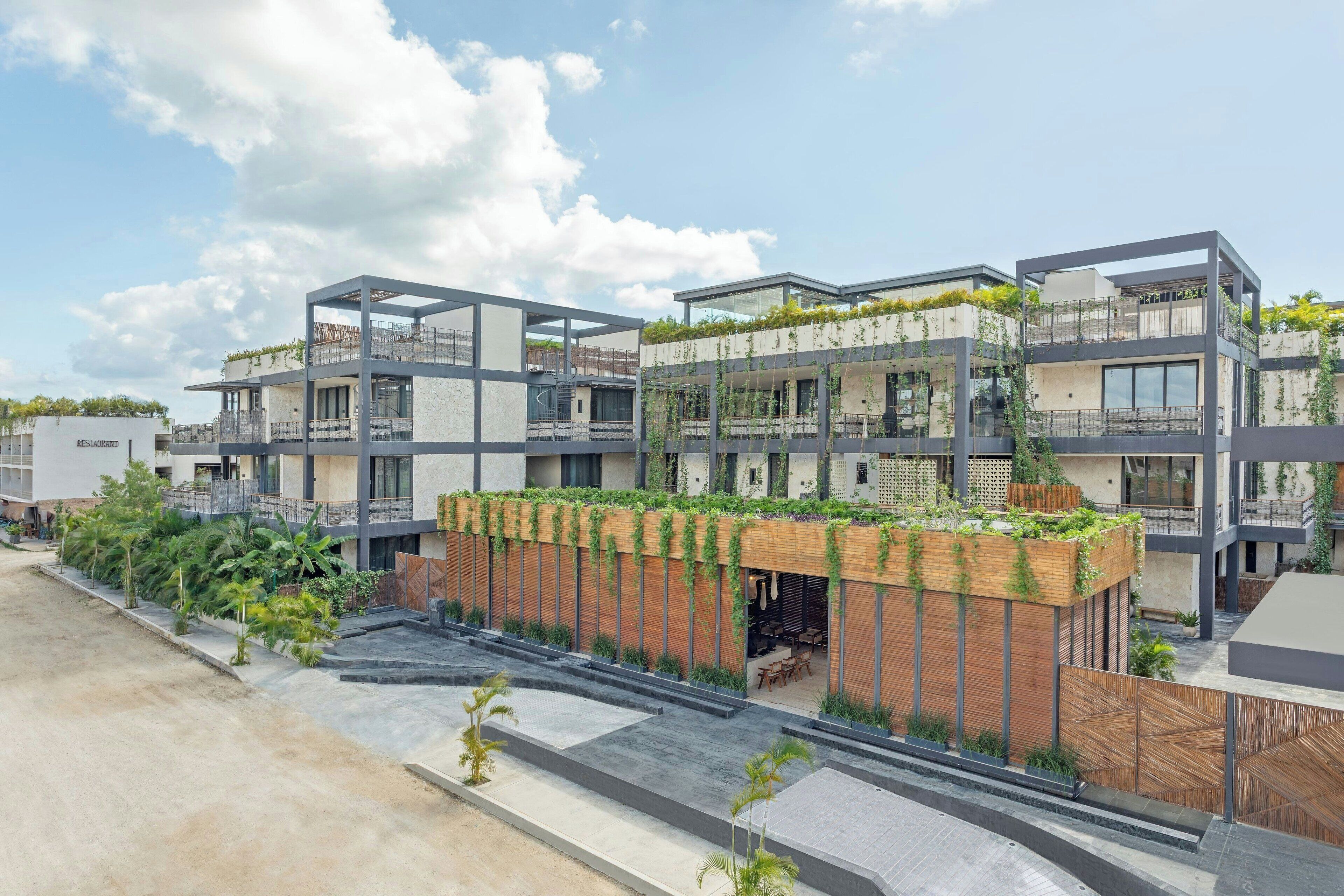A modern multi-story building with balconies, outdoor seating, and greenery.