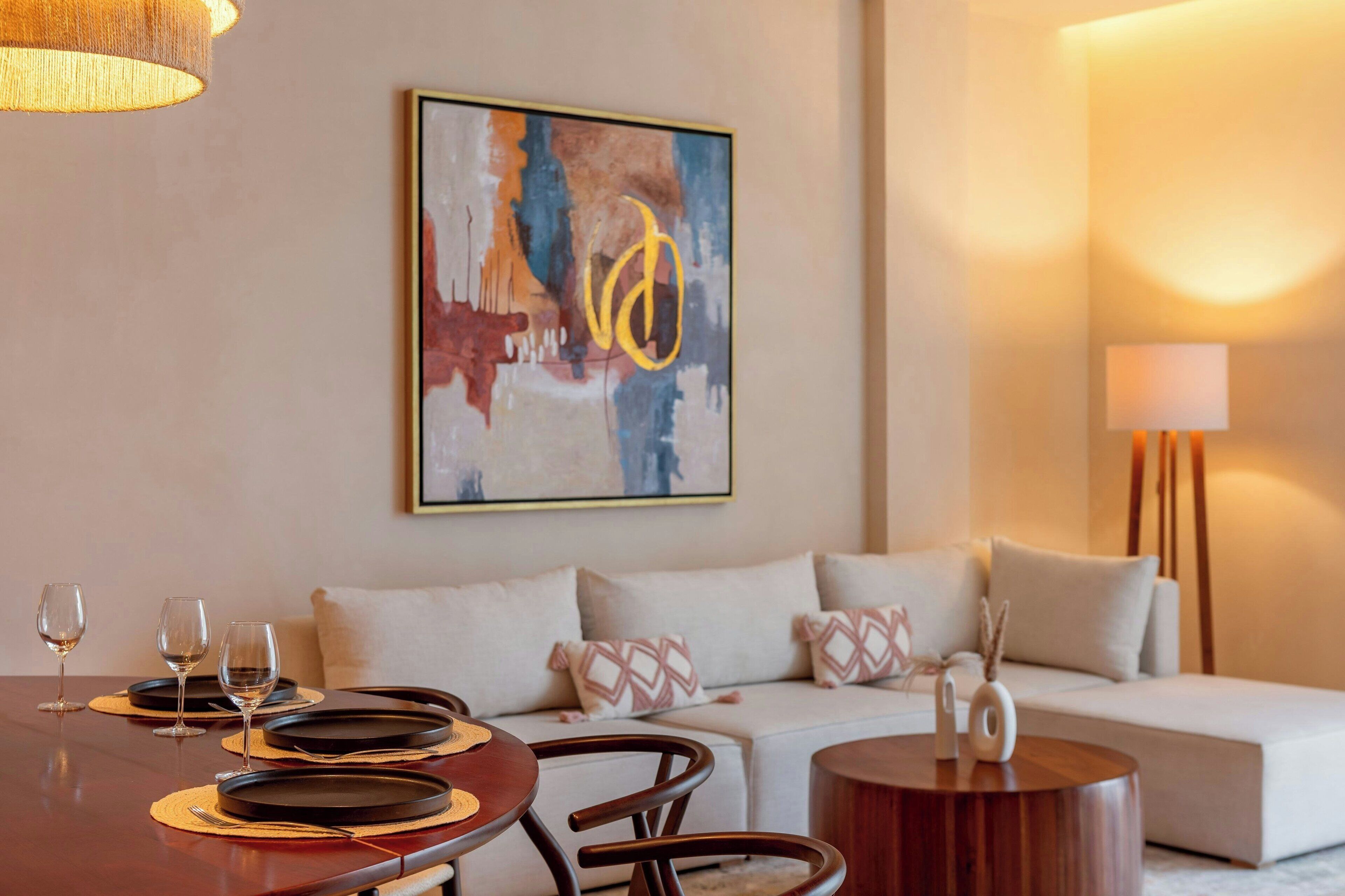 A dining area with a table set for four, a sofa, and a lamp.