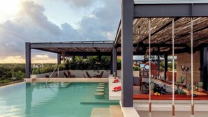 Zona de piscina exterior moderna amb una zona de seients coberta i un bar.