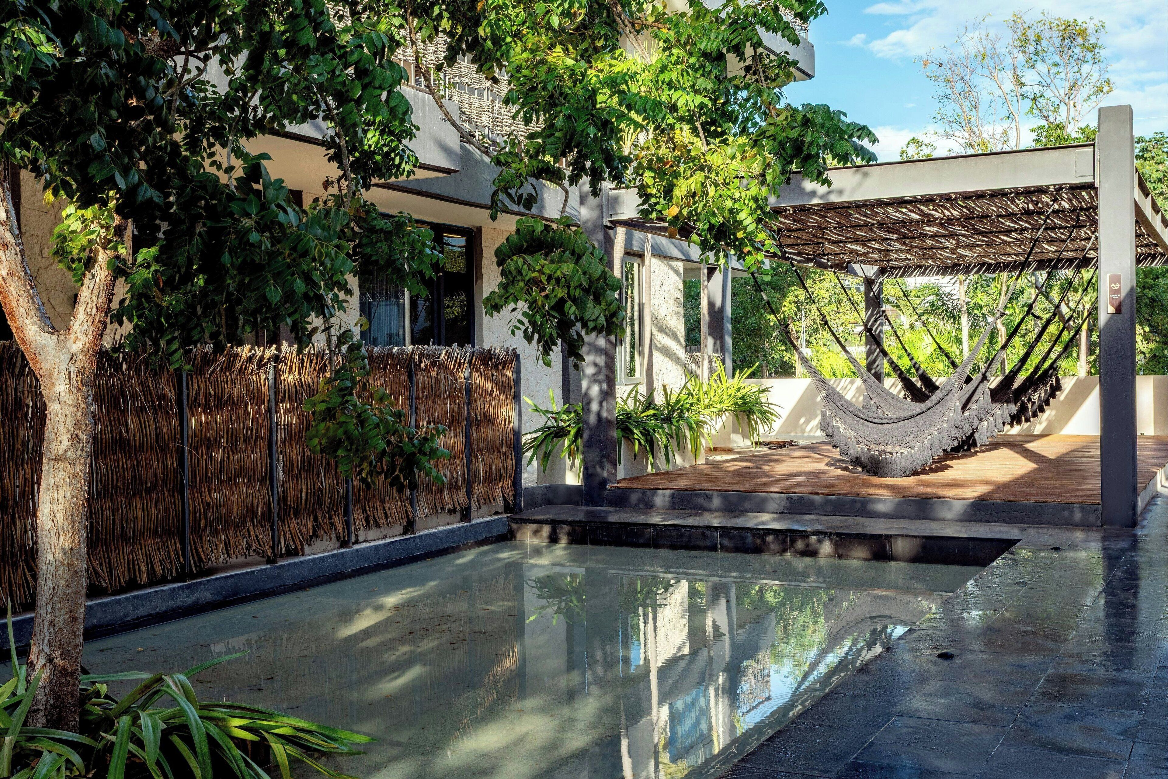 A serene indoor pool area with a clear view of the sky, surrounded by lush greenery and a modern architectural design.