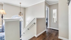 A staircase with a wooden floor, white walls, and a chandelier. - Fun & Cozy Retreat: Nature & Games (Quinte West)