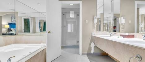 A modern bathroom with a large bathtub, a separate shower area, and a vanity with a mirror.