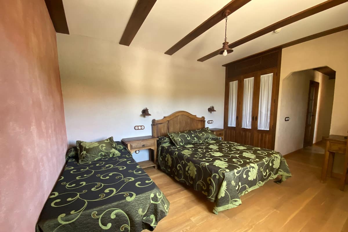 Un dormitorio con dos camas individuales, cabeceros de madera, mesitas de noche pequeñas y un ventilador de techo.