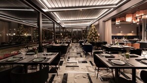 A modern restaurant with a long dining area, large windows, and a Christmas tree. - Demi Hotel (Sarandë)