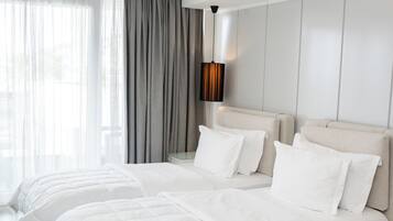 Quarto de hotel moderno com uma cama grande, um sofá e vista para o exterior.