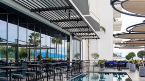 A rooftop pool area with bar seating and a view of the ocean. - Demi Hotel (Sarandë)
