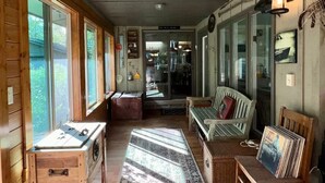 A wooden interior with a long corridor, wooden benches, a table with a laptop, and a rug. - Hot Tub in the Forest Cozy Home on Peaceful Lake (Mountain)