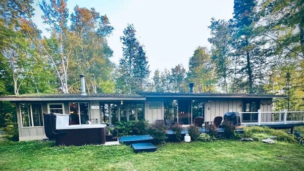 A single-story house with a covered porch, a small deck, and a backyard with a grill and outdoor seating. - Hot Tub in the Forest Cozy Home on Peaceful Lake (Mountain)