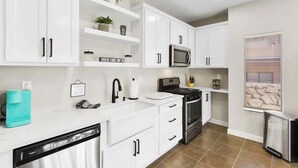 A modern kitchen with white cabinets, a microwave, stove, and a dishwasher. - Charming 4BR Near Fort Bliss (El Paso)