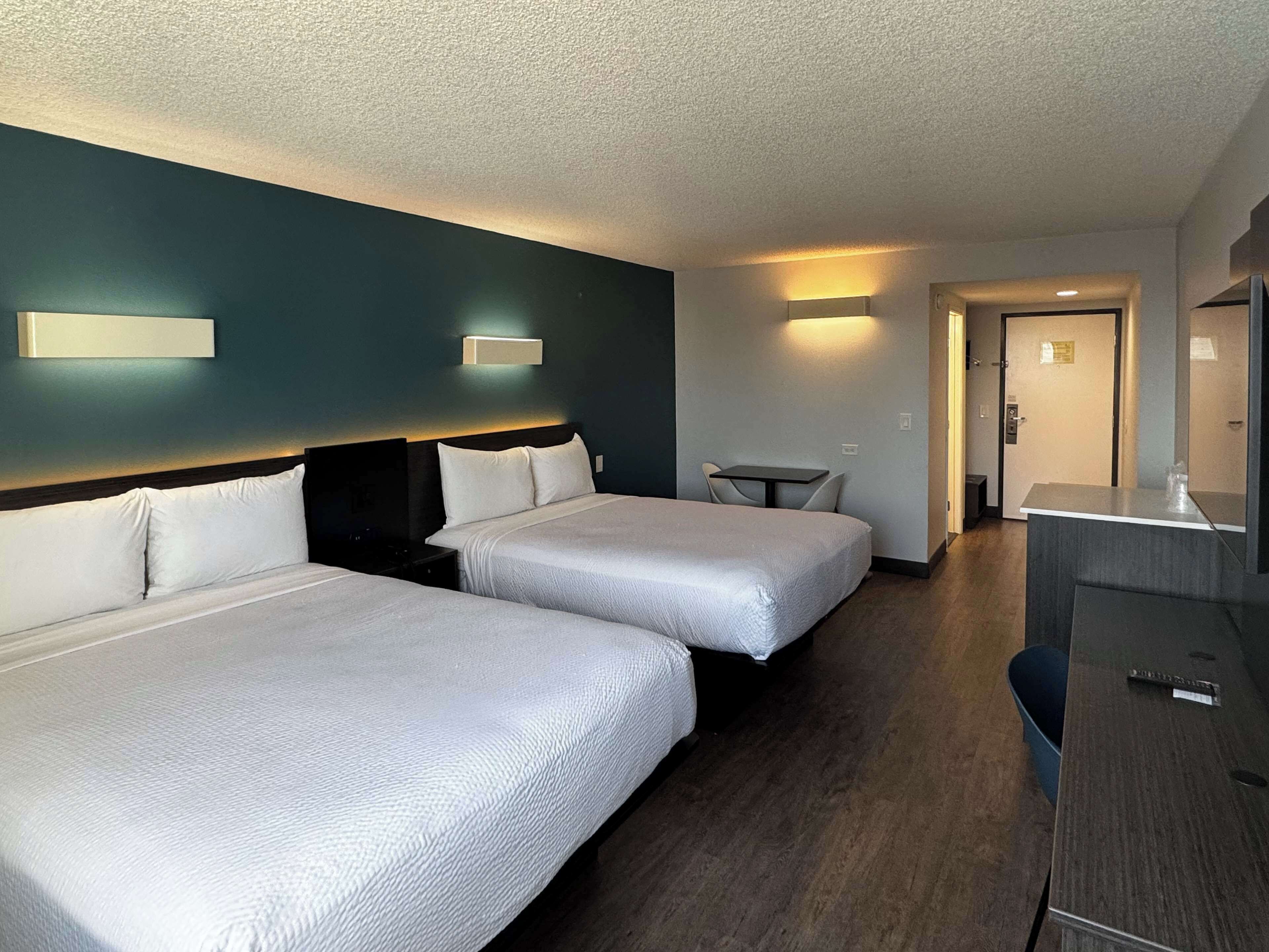 A hotel room with two beds, a desk, and a chair.
