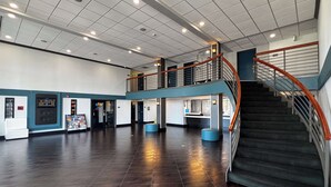 A spacious lobby with a central staircase, a reception desk, and a vending machine. - Studio 6 Carson, CA (Carson)