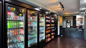 A row of beverage vending machines with various drink options and a snack shelf to the right. - Studio 6 Carson, CA (Carson)