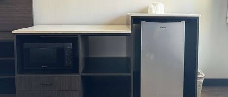 A compact kitchenette with a microwave, a refrigerator, and a small countertop.
