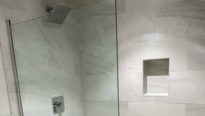 A glass-enclosed shower with a handheld showerhead and a control panel. - The Pelican Villa (Nassau)