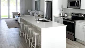 A modern kitchen with a central island, stainless steel appliances, and white cabinetry.