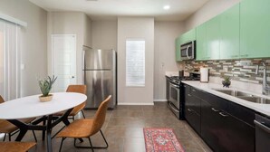Una cocina moderna con comedor, electrodomésticos de acero inoxidable y armarios verdes.