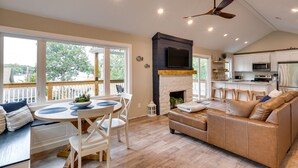 A spacious living area with a fireplace, a dining table with chairs, a sofa, and a kitchen area with modern appliances. - Lakefront Home w/ Private Dock in Sunrise Beach! (Sunrise Beach)