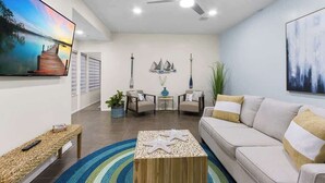 Uma sala de estar com sofá, mesa de centro, televisão e objetos decorativos.