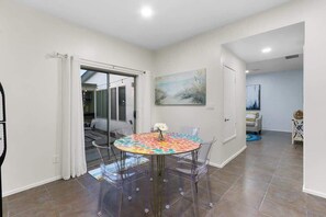 A dining area with a round table, clear chairs, and a glass partition.