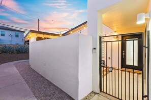 A modern building with a white exterior, a gated entrance, and a visible porch area.
