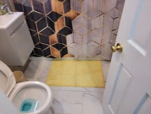 Ein Badezimmer mit Toilette, Waschbecken und einer Duschvorhang mit geometrischem Muster.