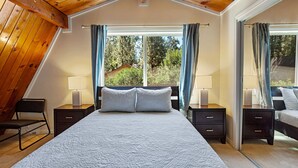 Un dormitorio con una cama grande, dos mesitas de noche, una silla y una ventana con cortinas.