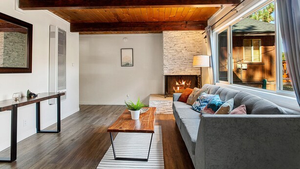 Una sala moderna con chimenea, techo de madera y un ventanal grande.