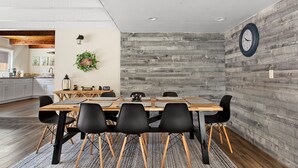 Un comedor con una mesa de madera, sillas negras y un reloj en la pared.