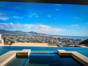 A swimming pool with a view of a cityscape and mountains in the background.