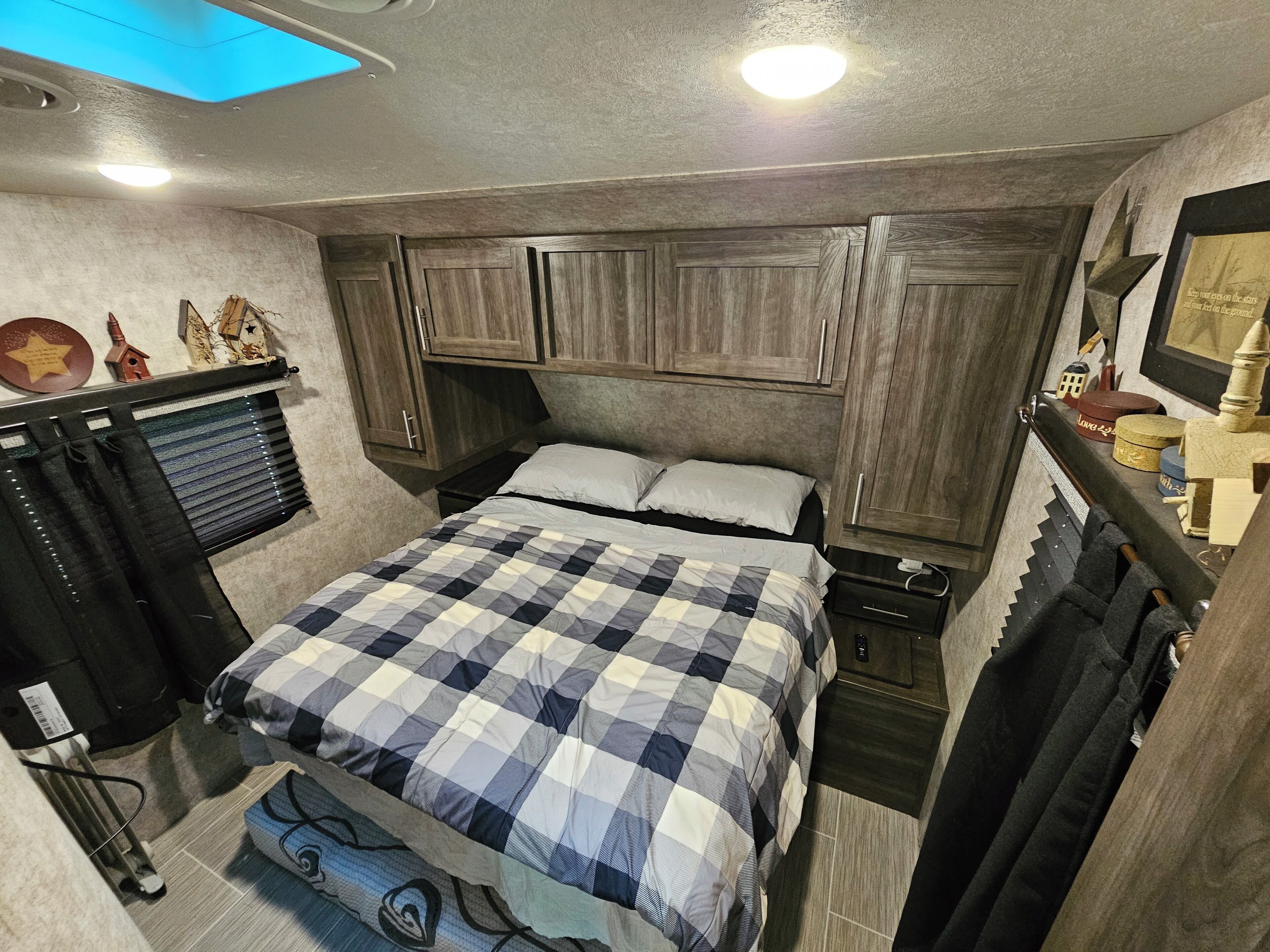 Ein kleines Schlafzimmer mit einem Bett, Holzschränken, einer kleinen Kommode und einem Fenster mit Vorhängen.