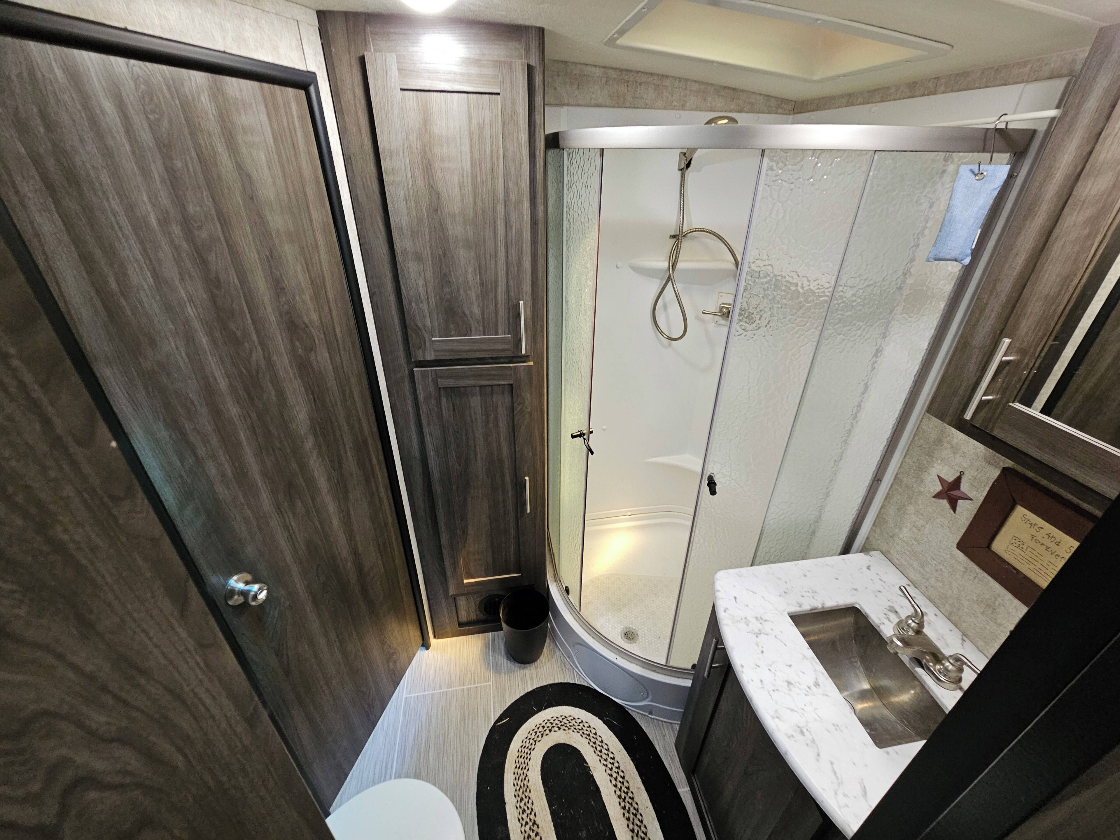 A bathroom with a shower, toilet, sink, and a mirror.