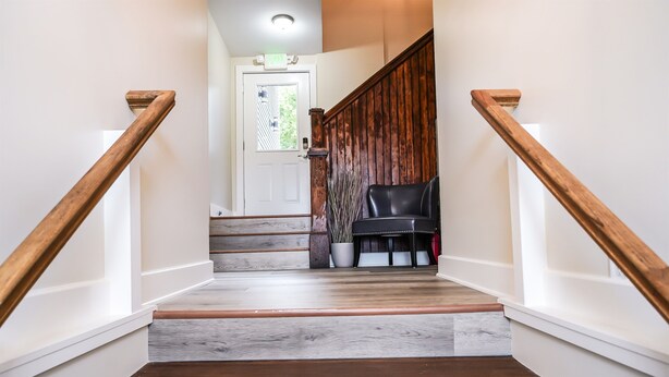 Un escalier avec des rampes en bois et un fauteuil en cuir noir au sommet.