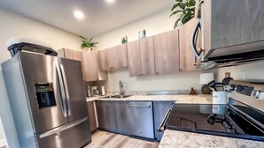 Une cuisine moderne dotée d’appareils électroménagers en acier inoxydable, d’armoires en bois et d’un plan de travail en marbre.