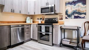 A modern kitchen with stainless steel appliances, wooden cabinets, and a wooden countertop. - Coastal Purple: Minutes to Cedar Point & Sports Complex! Sleeps 9 (Sandusky)
