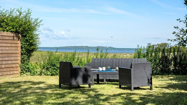 Un espace extérieur aménagé avec des meubles en osier et offrant une vue sur la mer.