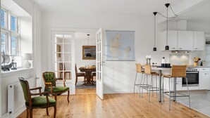 Une cuisine moderne avec des meubles blancs, un coin repas doté d’une table et de chaises en bois, et une grande carte accrochée au mur.