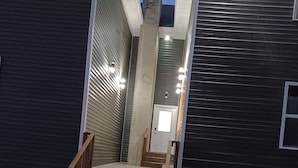 Una scala conduce a un edificio scuro, con una porta e una piccola finestra.