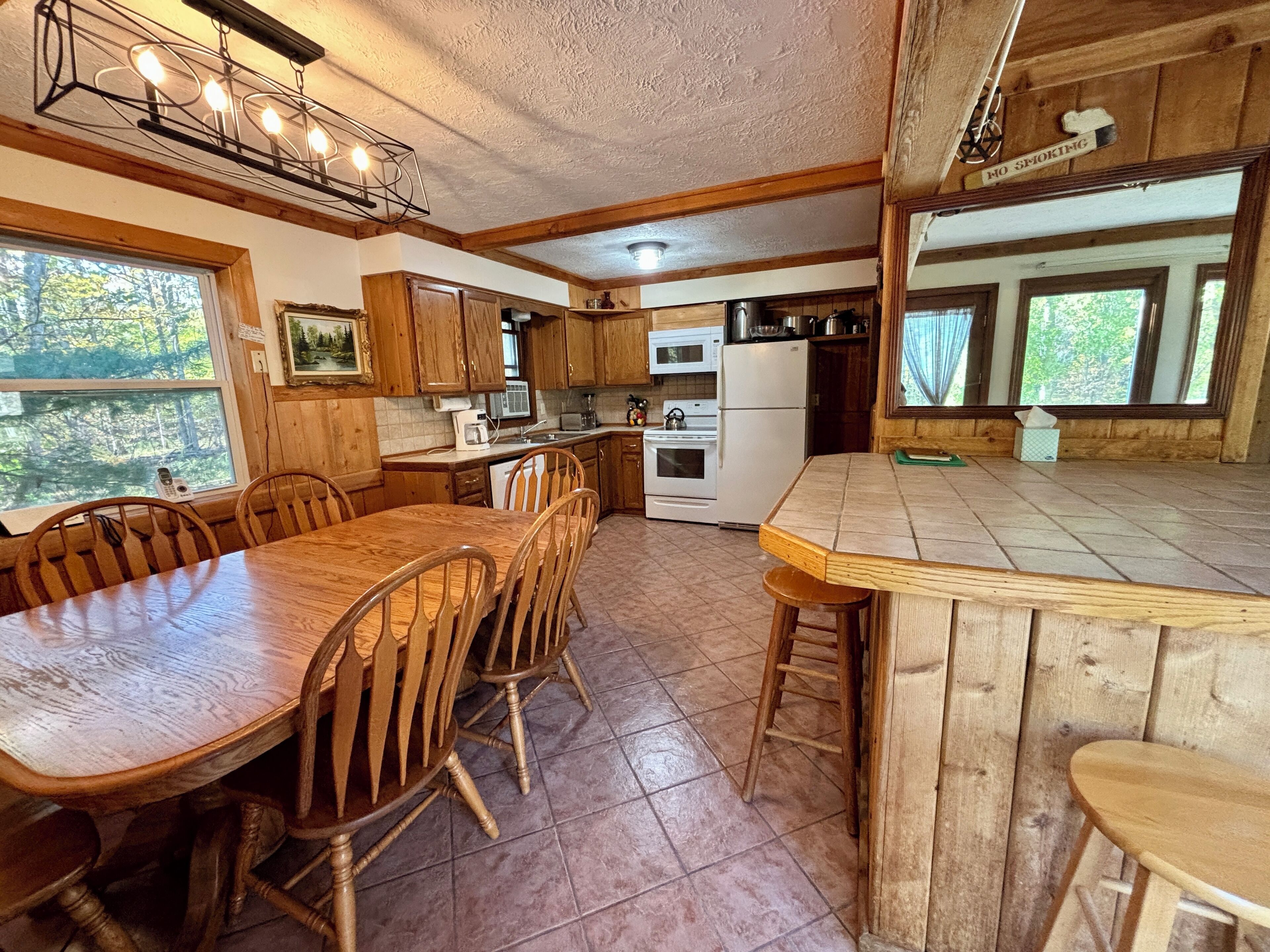 A rustic kitchen with wooden cabinets, a large dining table, and a bar area.