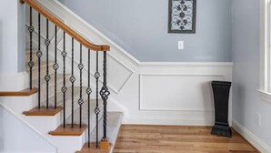 A staircase with wooden steps and black balusters, leading to a landing with a framed picture. - Lake Carolina Condo | 3BR 2.5BA (Columbia)