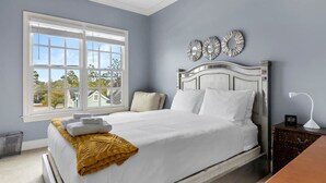 A bedroom with a large window, a bed with white bedding, a yellow throw blanket, and decorative wall art. - Lake Carolina Condo | 3BR 2.5BA (Columbia)
