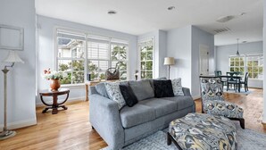 A spacious living room with a grey sofa, patterned ottoman, and a dining area with a table and chairs. - Lake Carolina Condo | 3BR 2.5BA (Columbia)