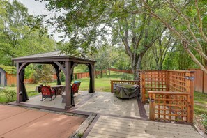 Relax in a serene outdoor patio area with a covered seating space and lush green surroundings.
