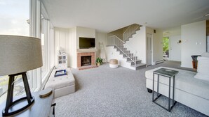 Uma sala de estar moderna com lareira, escada e uma janela grande.