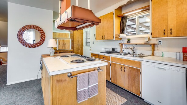 Une cuisine avec des meubles de rangement en bois, une cuisinière, un évier et un lave-vaisselle.