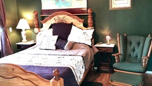 A neatly made bed with a wooden headboard, a green upholstered chair, and a map on the wall. - Millers' Misfit Farm (Prineville)