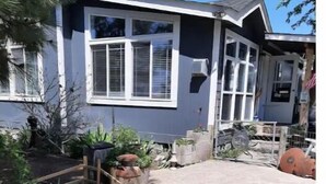 A residential property with a garden area, a wooden fence, and a house with a dark exterior and white trim. - Millers' Misfit Farm (Prineville)