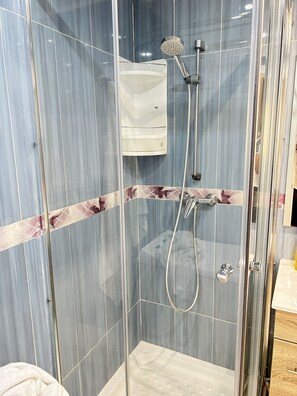Shower features a handheld showerhead and wall-mounted faucet with chrome finishes, alongside a marble-like tile pattern and decorative geometric design.
